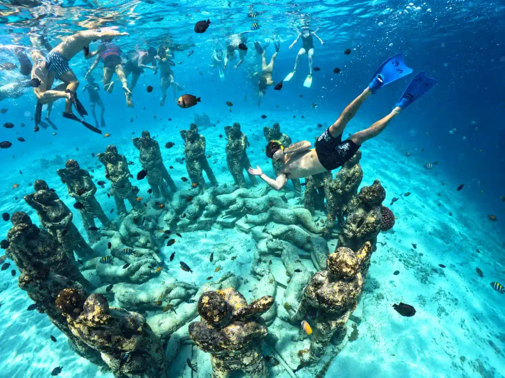Snorkeler near an underwater statue